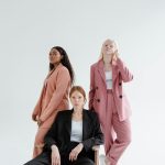 Three diverse businesswomen in stylish suits on a studio white background, exuding confidence.